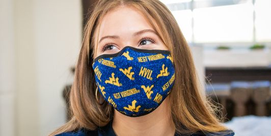 A student wearing a WVU branded mask in a WVU Potomac State College dorm room