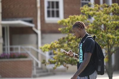 Student walking by the Administration Building looking at his phone.